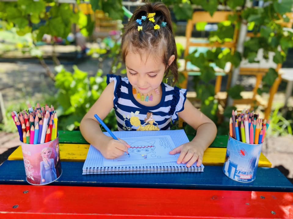 Copil desenând cu creioane colorate.