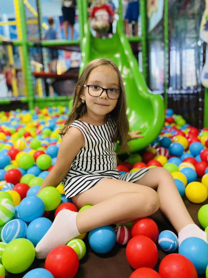 Fată jucându-se în mingi colorate.