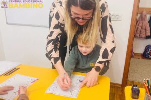 Copil ajutat de o profesoara de la Bambino sa deseneze